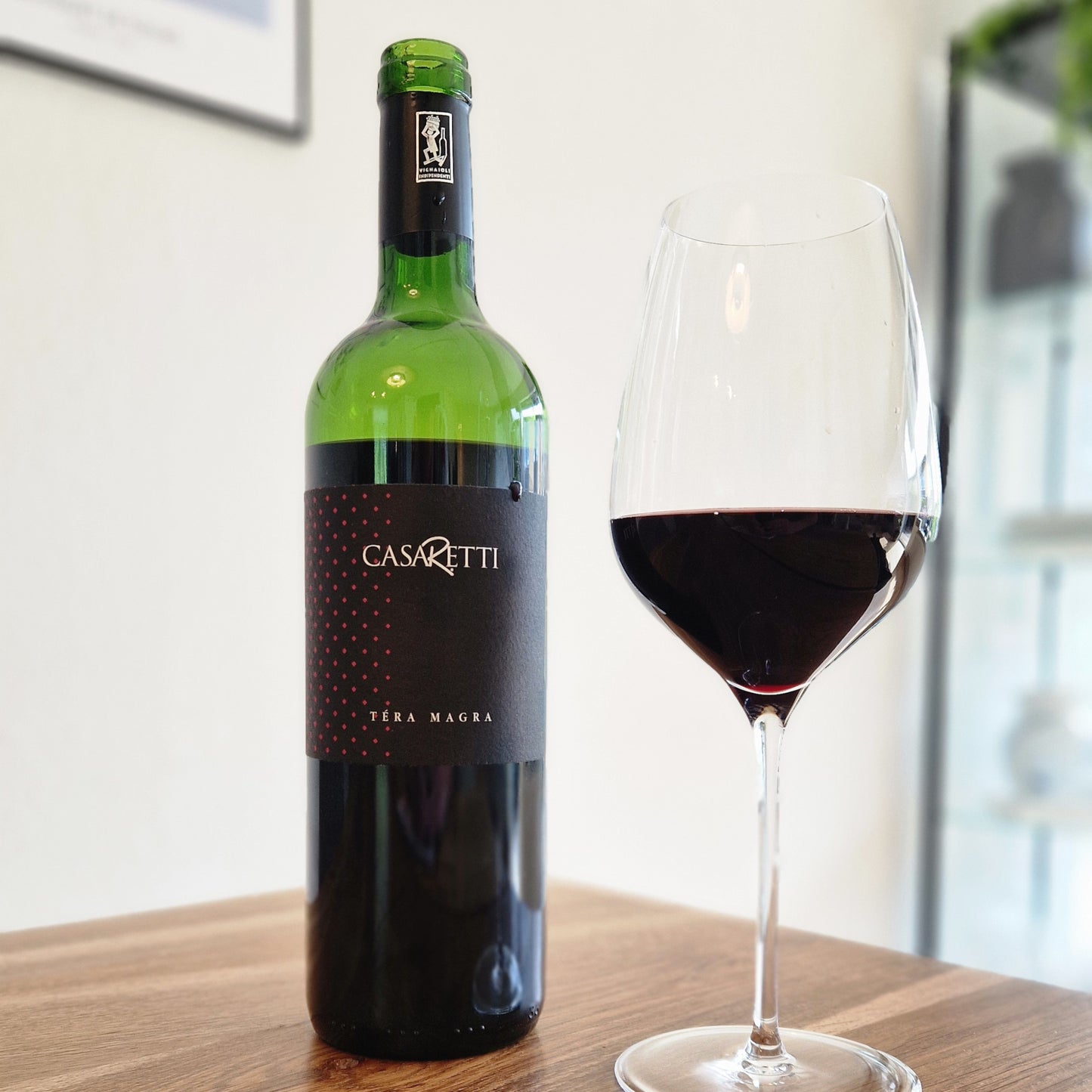 Casaretti wine bottle with a glass of red wine on a wooden table