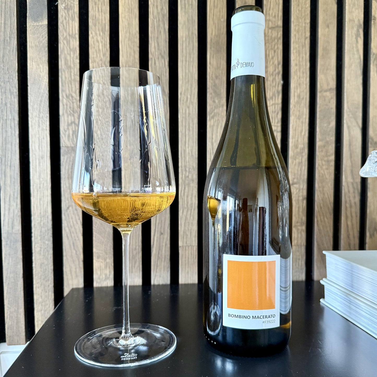 Wine bottle and glass with white wine on a wooden background