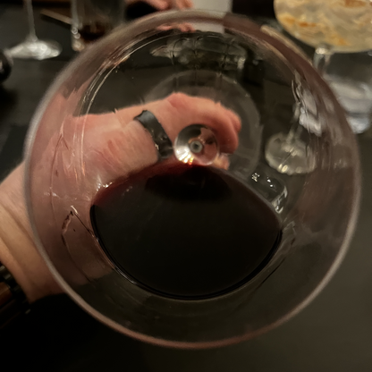 A minimalist overhead top view looking straight down into an elegant wine glass filled with rich, dark red Vaona Recioto wine, capturing the depth of its color against a clean surface.