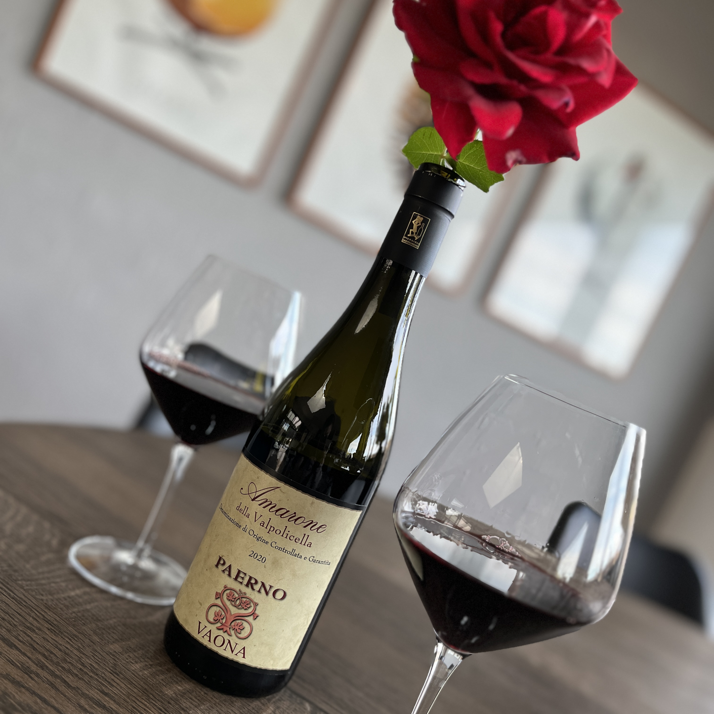 An alternative angle of the wooden table arrangement, showcasing the red wine glasses and opener, with the red rose now resting directly on the neck of the Vaona Amarone wine bottle.